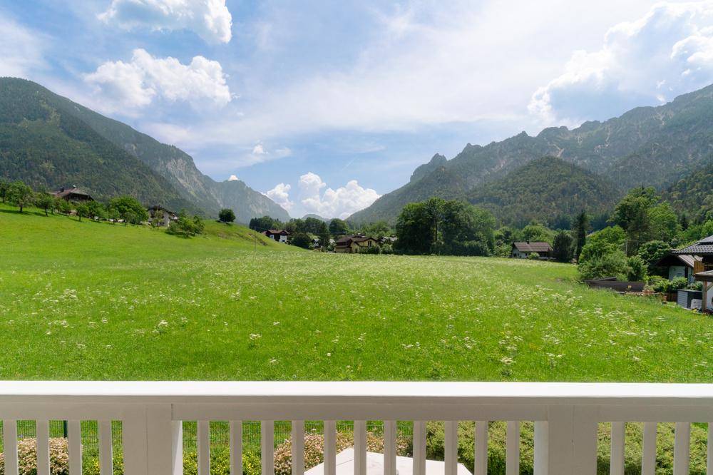 Atemberaubender Blick von einem Balkon über weite grüne Wiesen und majestätische Berge.