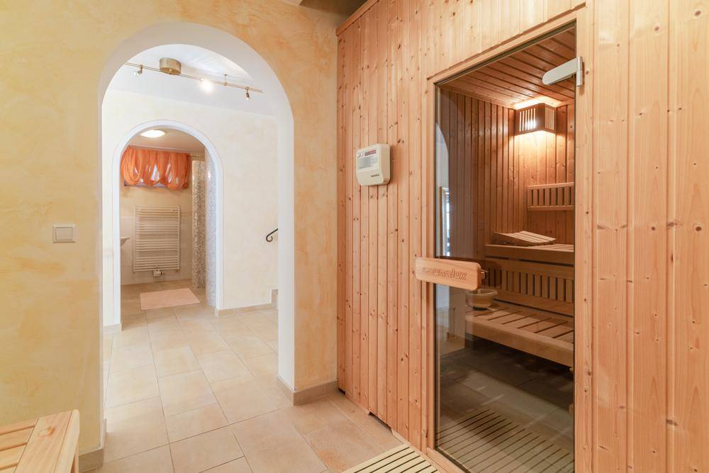 Entspannender Wellnessbereich mit holzverkleideter Sauna und Zugang zu einem Duschbereich.