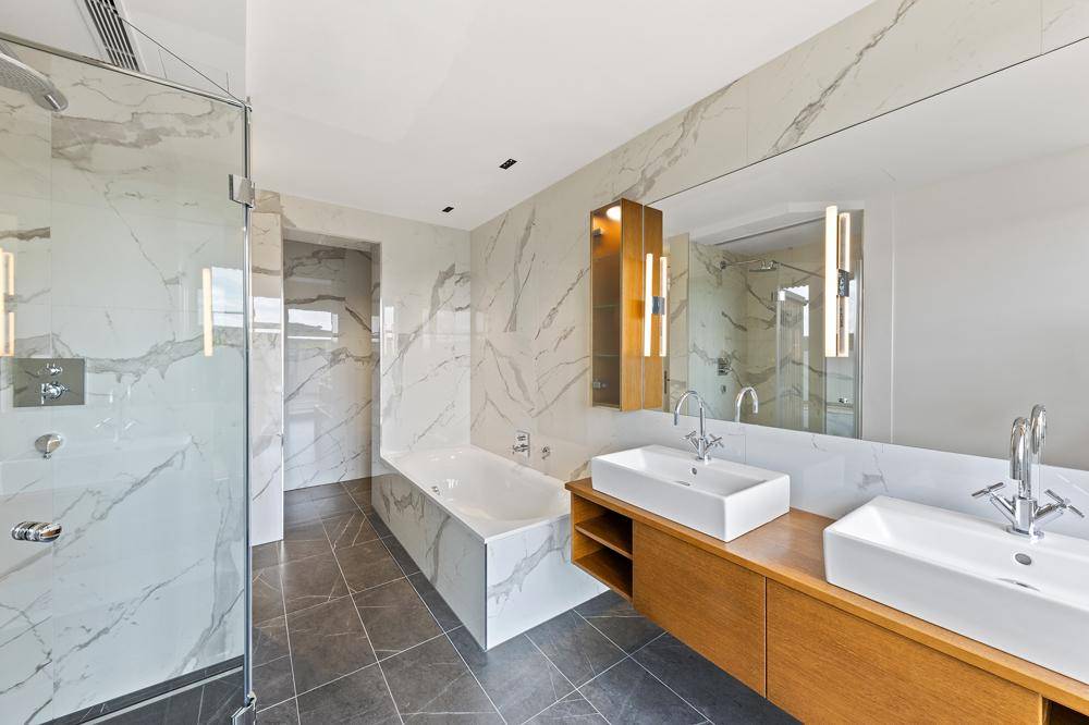 Modernes Badezimmer mit Marmorfliesen, begehbarer Dusche und Doppelwaschbecken.