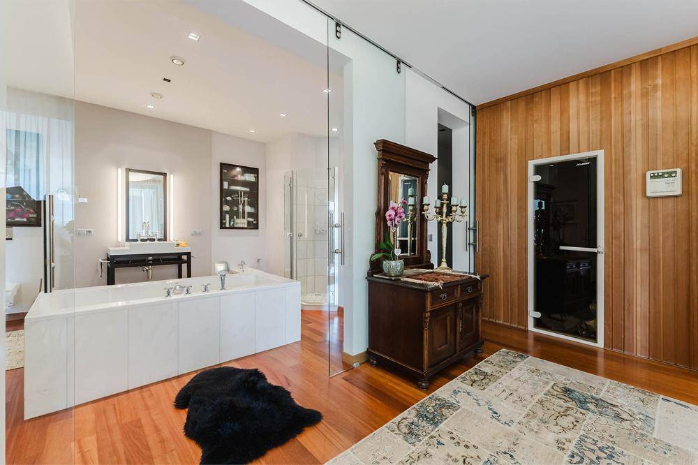 Luxuriöses Badezimmer mit Badewanne, Doppelwaschbecken und integrierter Sauna für Wellnessmomente.