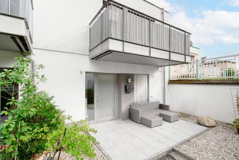 Kleine, gepflasterte Terrasse mit modernen Outdoor-Möbeln und Zugang zum Gebäude.