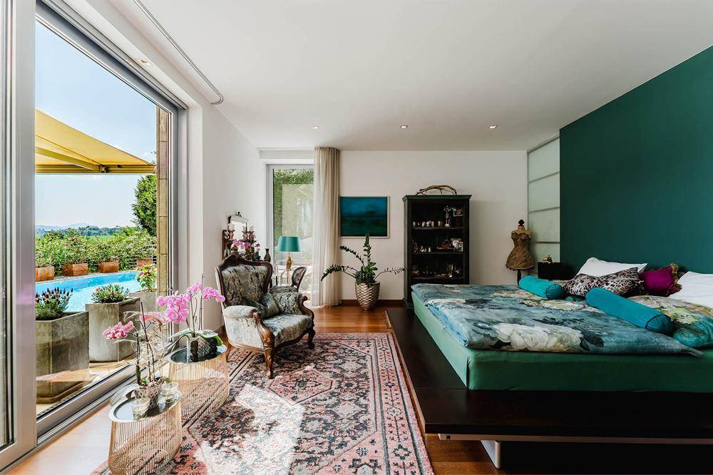 Geräumiges Schlafzimmer mit Zugang zum Balkon, Holzboden und farbiger Akzentwand.