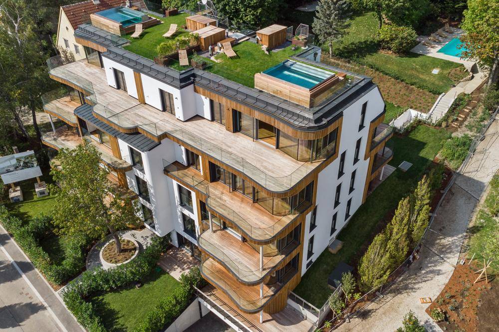Moderne Wohnanlage mit mehreren Balkonen, begrünten Dächern und Dachterrassen-Pools.