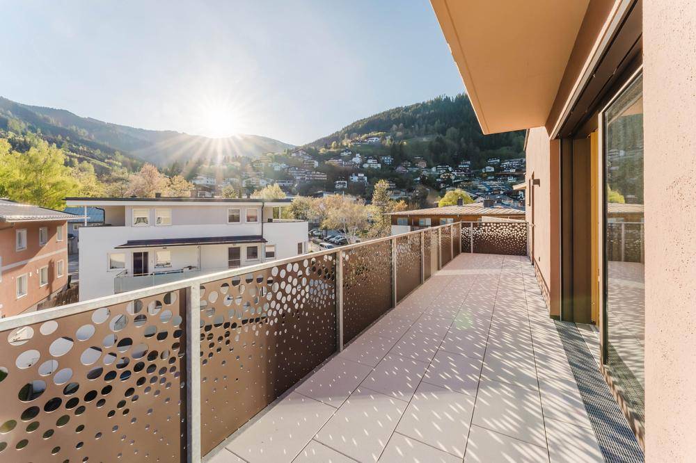 Großer Balkon mit moderner Lochblech-Brüstung und weitem Blick auf die umliegende Berglandschaft.
