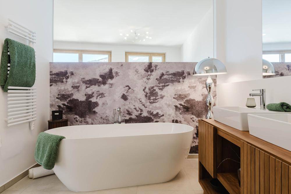Elegantes Badezimmer mit freistehender Badewanne, Doppelwaschbecken und einem praktischen beheizten Handtuchhalter.