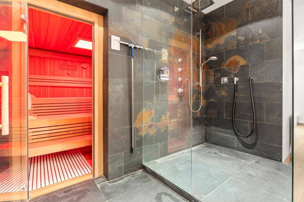 Luxuriöses Badezimmer mit begehbarer Dusche, Schieferfliesen und integrierter Sauna.