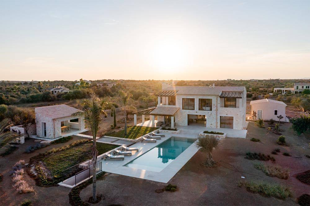 Luftaufnahme des Anwesens bei Sonnenuntergang mit Haupthaus, Pool und weitläufiger Landschaft.