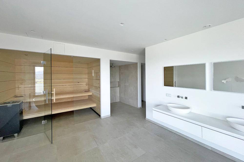 Geräumiges Badezimmer mit integrierter Sauna, Doppelwaschbecken und modernen Fliesen.