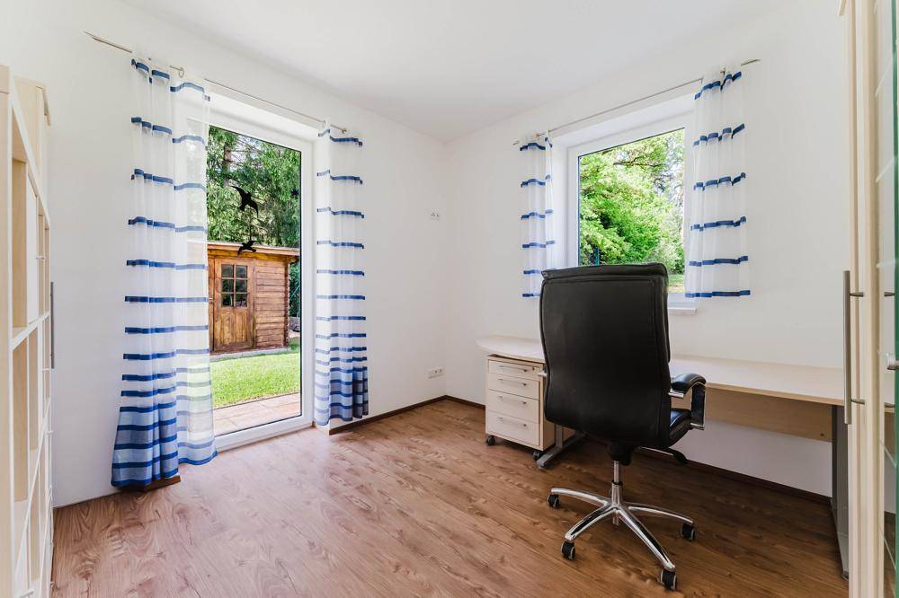 Helles Arbeitszimmer mit Holzboden, Fenster und direktem Zugang zum Garten.