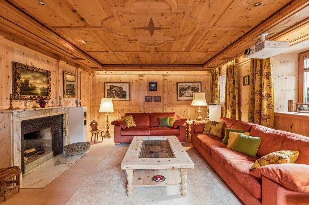 Traditionelles Wohnzimmer mit Holzwänden, Deckenvertäfelung, Kamin und bequemen Sitzgelegenheiten.
