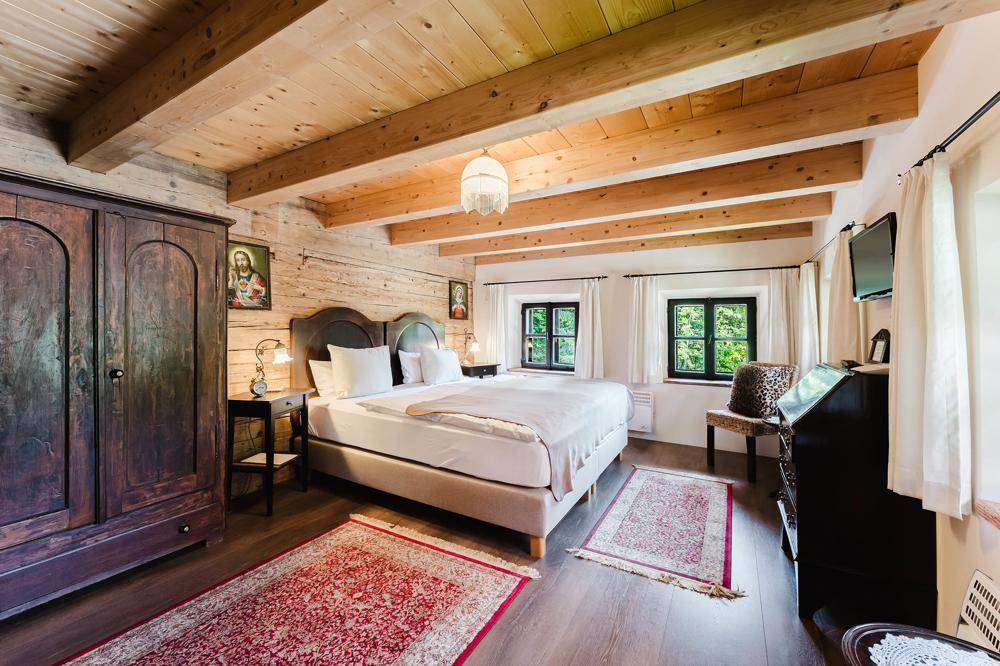 Gemütliches Schlafzimmer mit Holzbalkendecke, Holzwänden und traditionellen Teppichen.