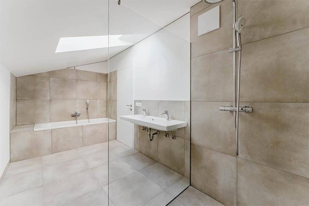 Modernes Badezimmer mit Dusche, Badewanne, Doppelwaschbecken und Dachfenster.