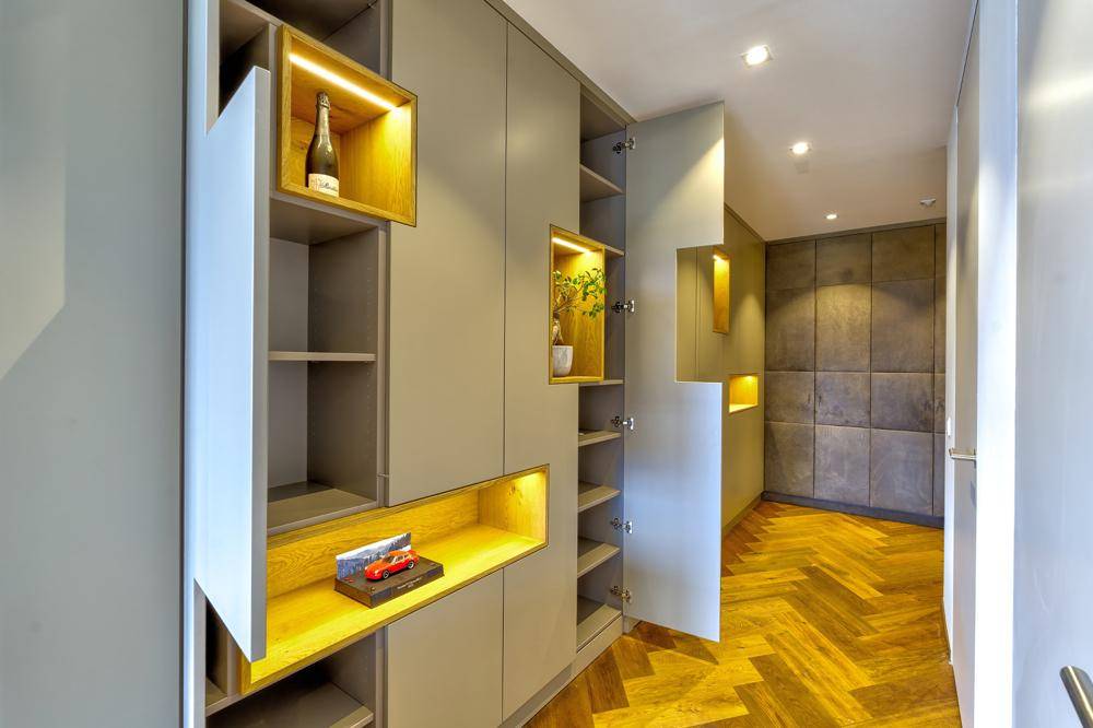 Offene Einbauschränke im Flur mit cleveren Staufächern und indirekter Beleuchtung über dem Fischgrätparkett.
