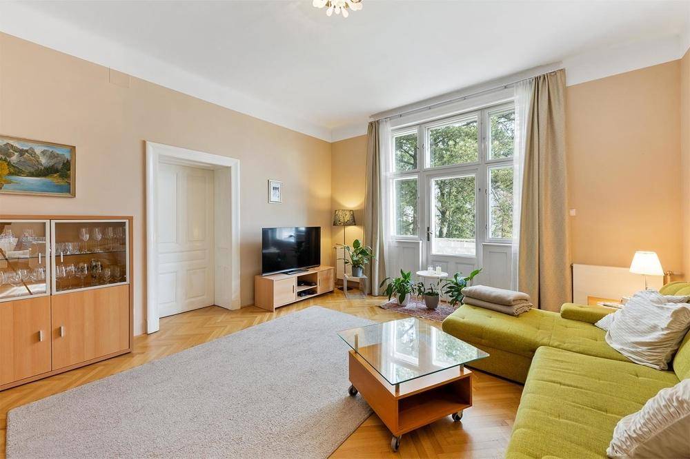 Gemütliches Wohnzimmer mit Parkettboden, großem Fenster und bequemer Sofalandschaft.