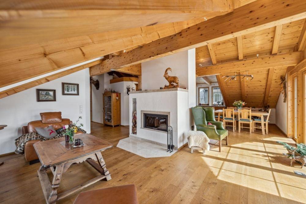 Geräumiger Wohn- und Essbereich im Dachgeschoss mit Holzbalken, Kamin und rustikalem Charme.