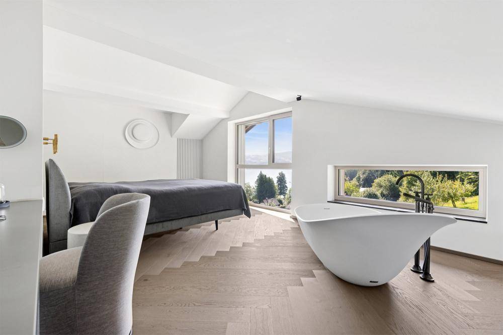 Geräumiges Schlafzimmer mit freistehender Badewanne, Dachschrägen und malerischem Ausblick.