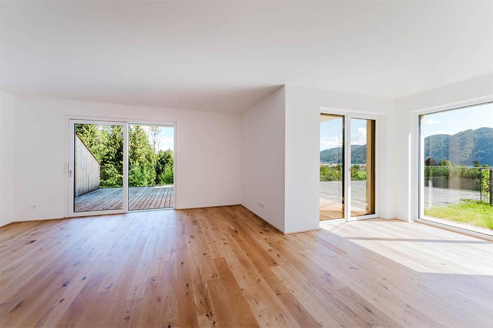Heller, leerer Wohnraum mit Eichenparkettboden und großen Schiebetüren zur Terrasse.