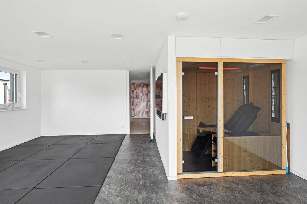 Geräumiger Raum mit integrierter Sauna und dunklem Boden, ideal als Fitness- oder Wellnessbereich.