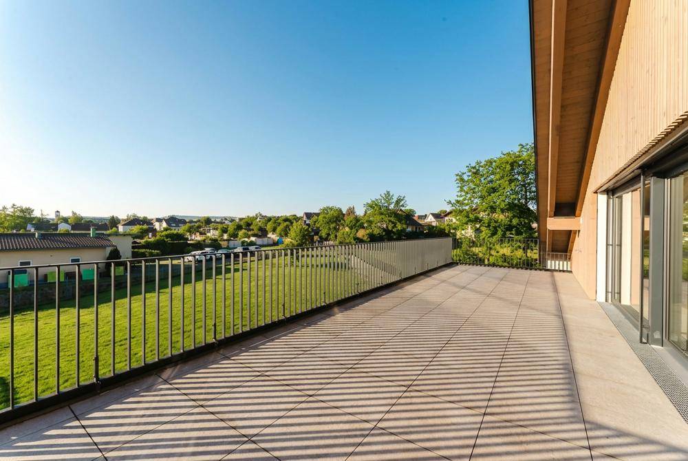 Geräumige Terrasse mit Blick auf die umliegende Wohngegend und viel Grün.