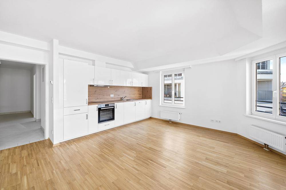 Moderne Einbauküche mit weißen Hochglanzfronten und Holzakzenten in einem hellen Raum.