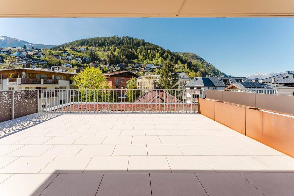 Weitläufige Terrasse mit moderner Metallbrüstung und Panoramablick auf die Berge und Dächer.