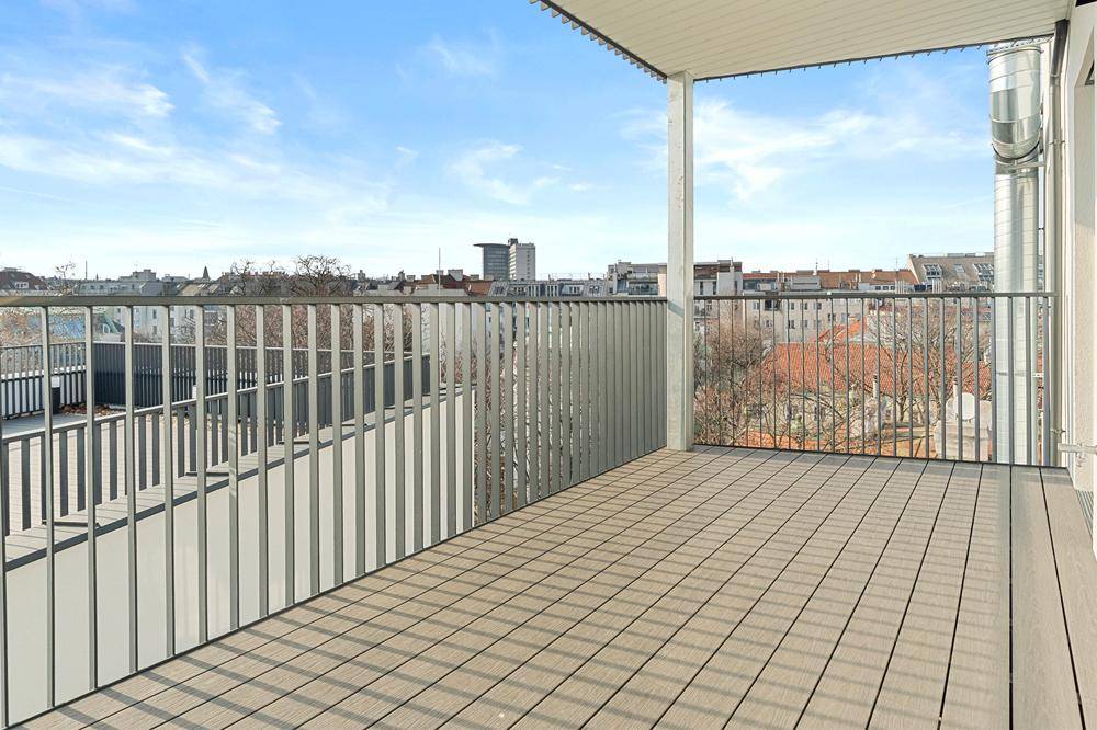 Geräumiger Balkon mit Holzboden und Metallgeländer, bietet einen weiten Blick über die Stadt.