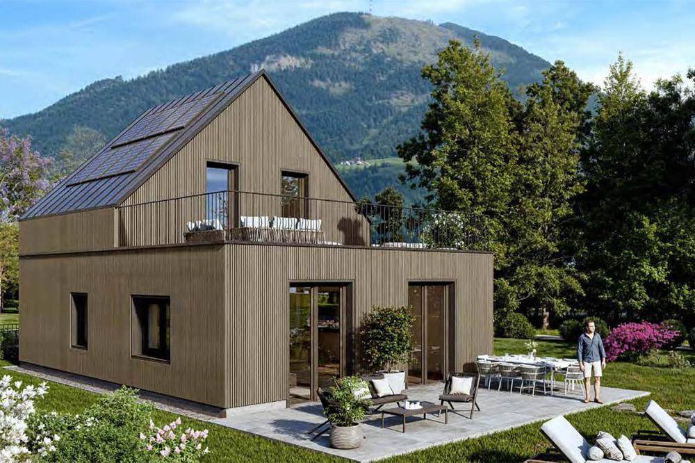 Modernes Haus mit Holzverkleidung, großzügiger Terrasse und Bergblick unter blauem Himmel.