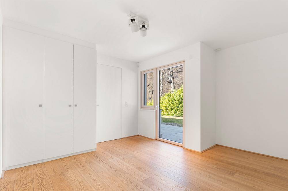 Helles Zimmer mit Einbauschränken, Holzboden und direktem Zugang zum Garten.