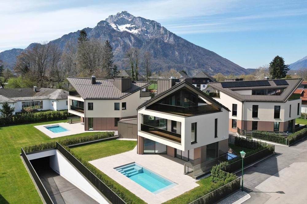 Moderne Wohnanlage mit mehreren Gebäuden, Pools und Bergblick in einer grünen Umgebung.