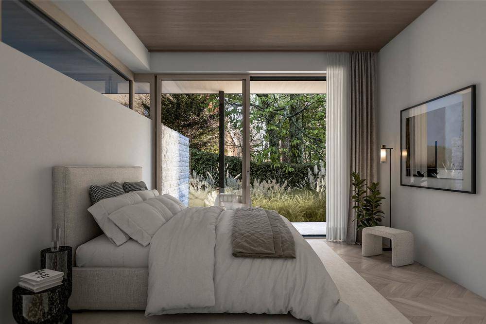 Helles Schlafzimmer mit Holzboden, großem Bett und direktem Zugang zu einem privaten Gartenbereich.
