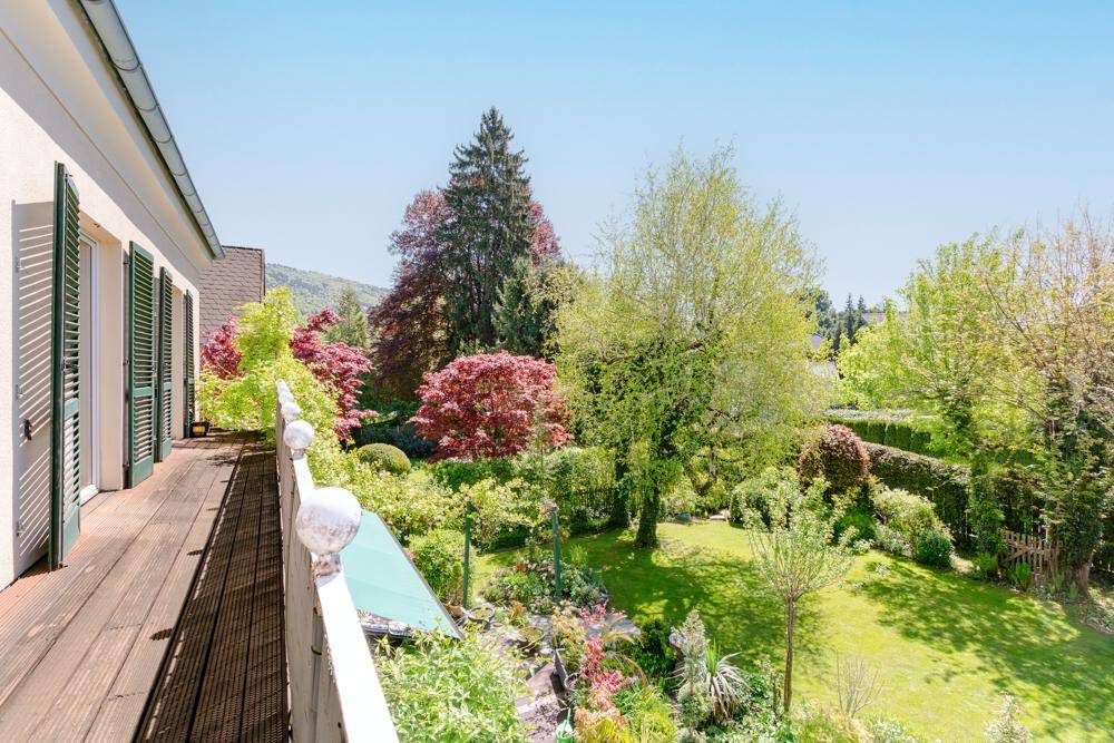 Balkon mit Holzboden und weitem Blick über den wunderschön angelegten, grünen Garten.