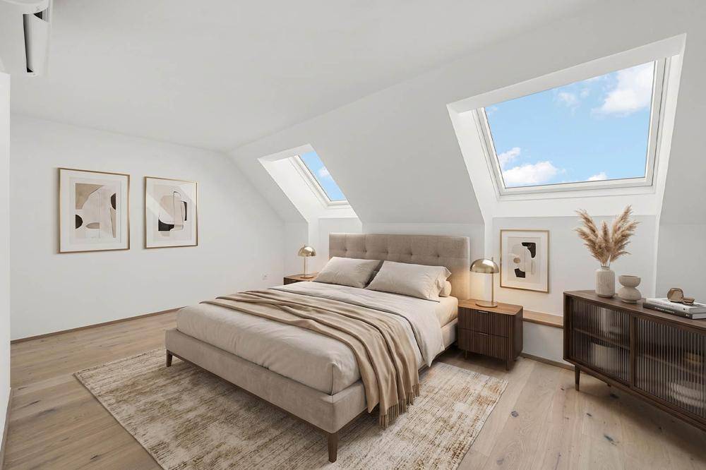 Helles Schlafzimmer mit gemütlichem Bett, Dachschrägen und großen Dachfenstern.