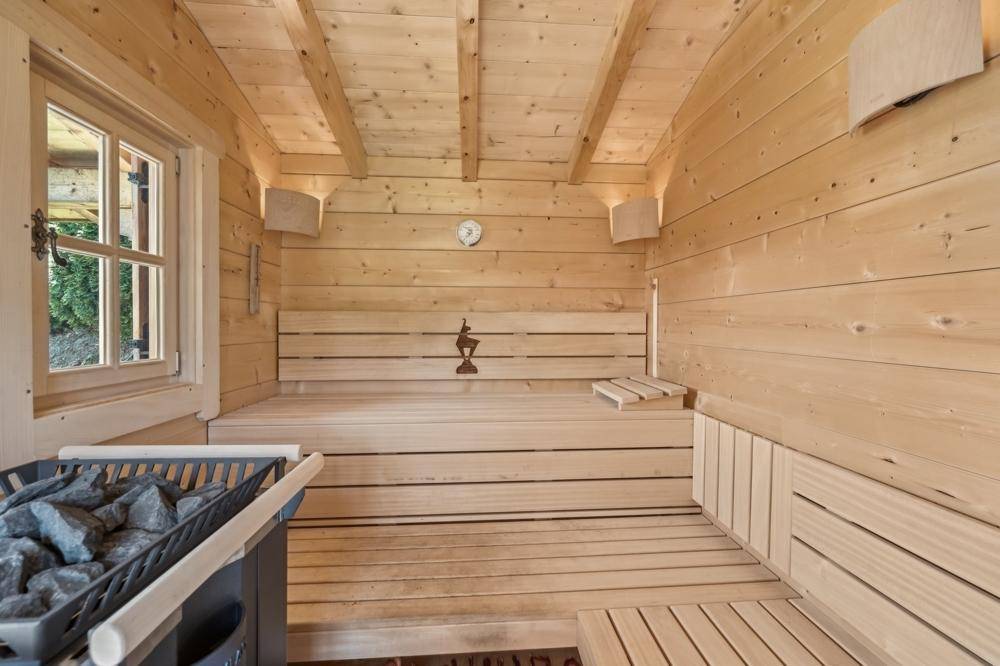 Traditionelle Holzsauna mit Bänken und Saunaofen für entspannende Momente.