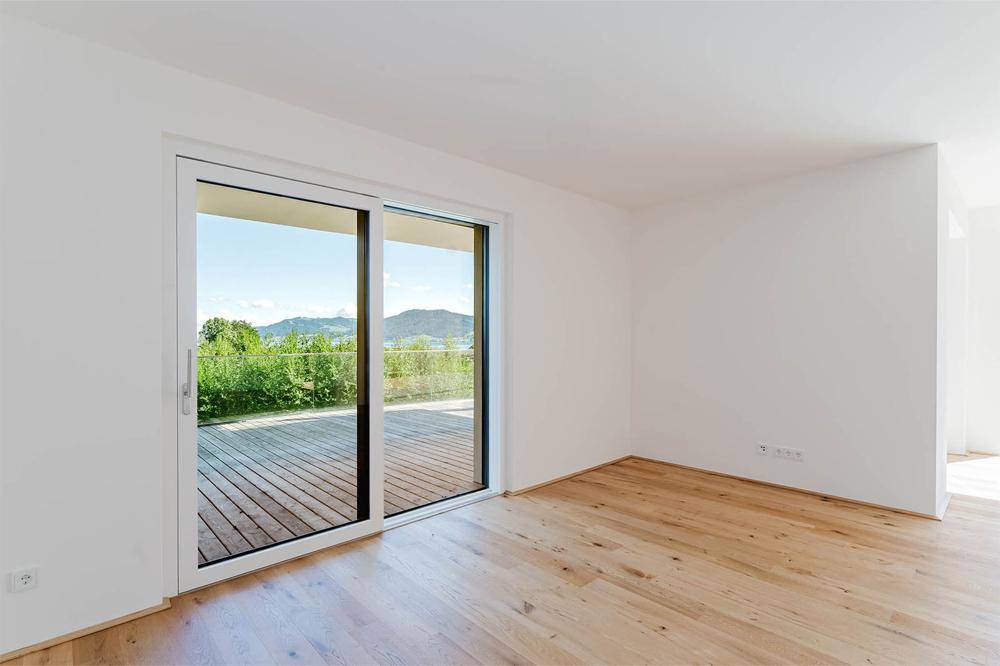 Heller Wohnbereich mit Holzboden und Zugang zu einer großen Außenterrasse.