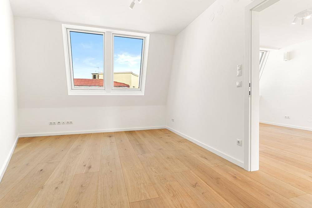 Helles Schlafzimmer im Dachgeschoss mit schrägen Wänden und großen Dachfenstern, bietet viel Tageslicht.