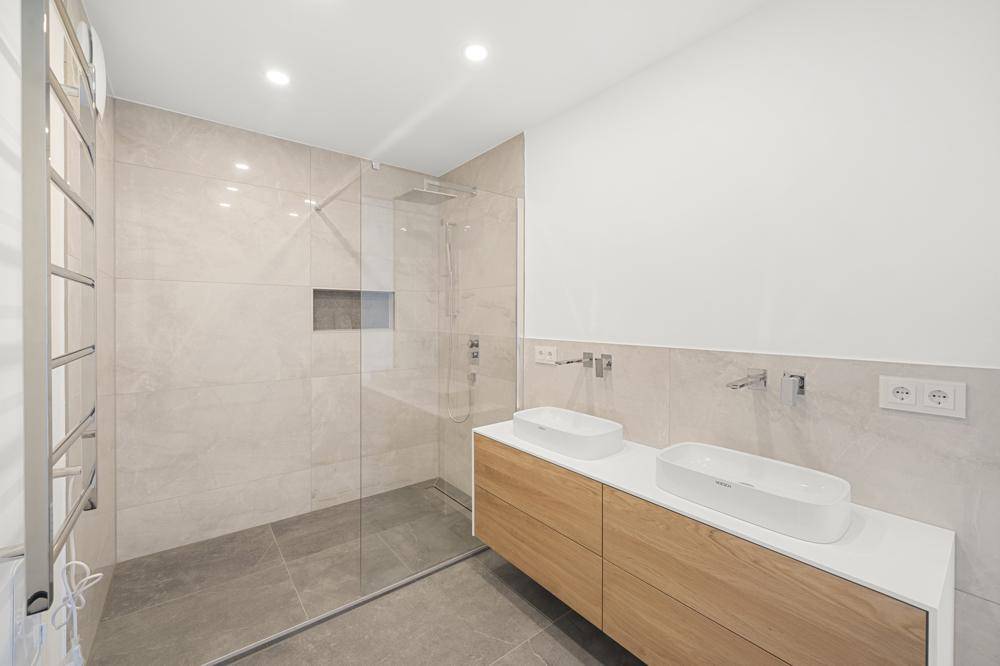 Modernes Badezimmer mit großer begehbarer Dusche, Doppelwaschbecken und Handtuchheizkörper.