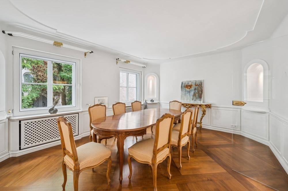 Elegantes Esszimmer mit großem Holztisch, Parkettboden und klassischen Wandverkleidungen.
