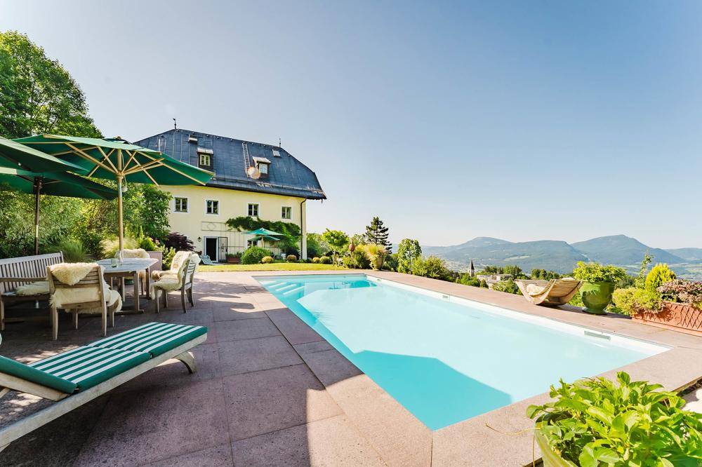 Außenpool mit Sonnenterrasse, Liegestühlen und Panoramablick auf die umliegende Berglandschaft.