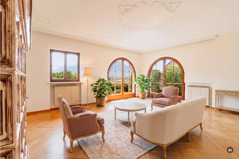 Elegantes Wohnzimmer mit Stuckdecke, Fischgrätparkett und großen Rundbogenfenstern mit Gartenblick.