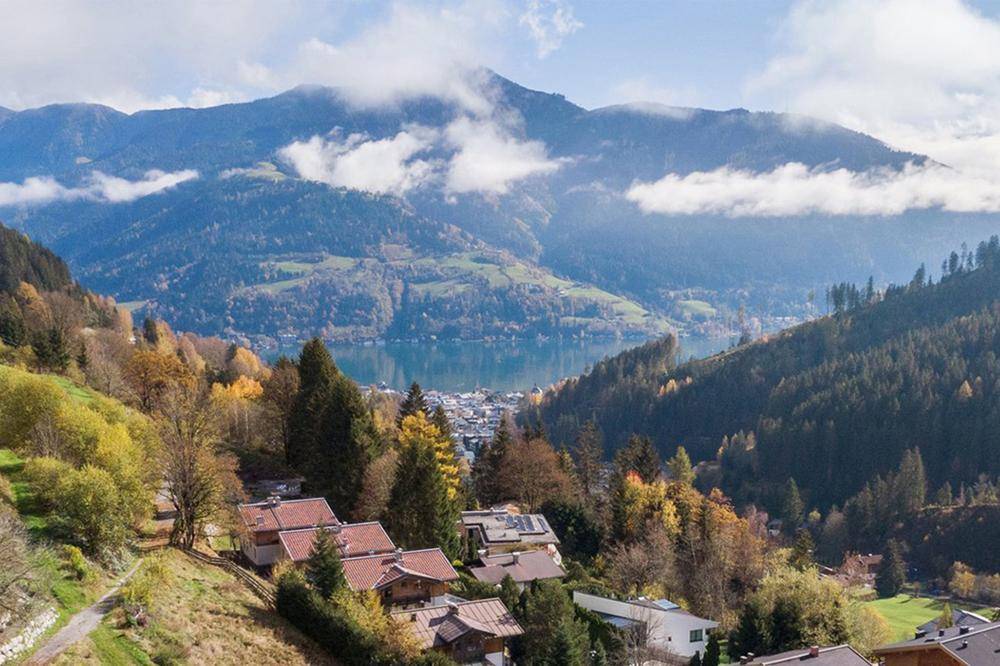 Luftaufnahme von Häusern am Hang mit weitem Blick auf einen See und die umliegende Berglandschaft.