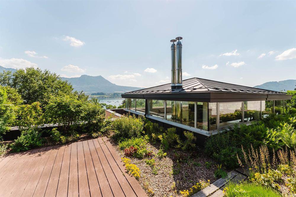 Moderne Architektur mit Flachdach und großen Glasflächen, eingebettet in eine grüne Gartenlandschaft.