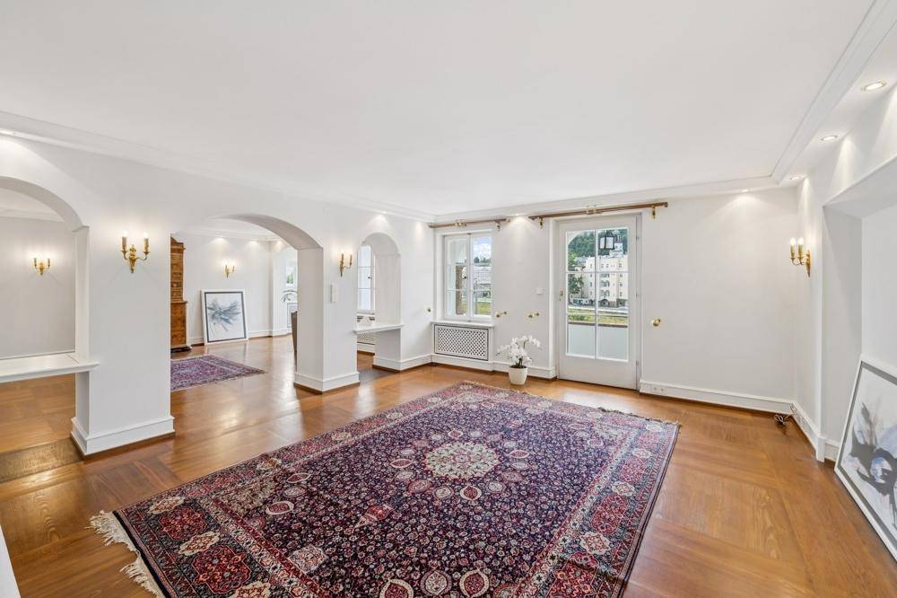 Geräumiges Wohnzimmer mit Parkettboden, dekorativem Teppich und französischen Balkonen.