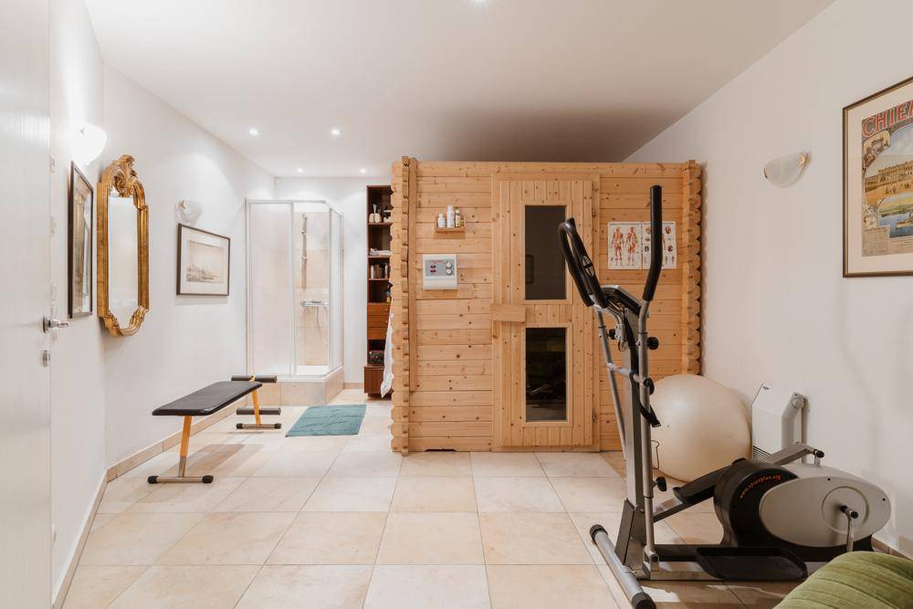 Privater Wellnessbereich mit Sauna, Dusche und verschiedenen Fitnessgeräten für Sport und Entspannung.