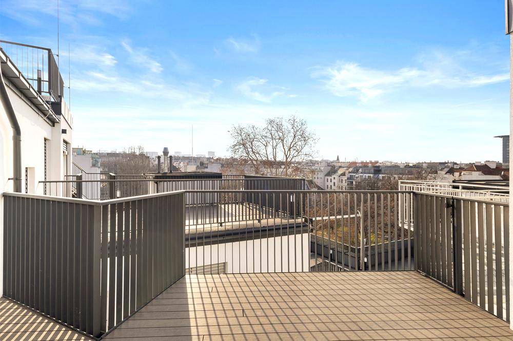 Geräumige Dachterrasse mit Holzboden und weitem Blick über die Stadt.