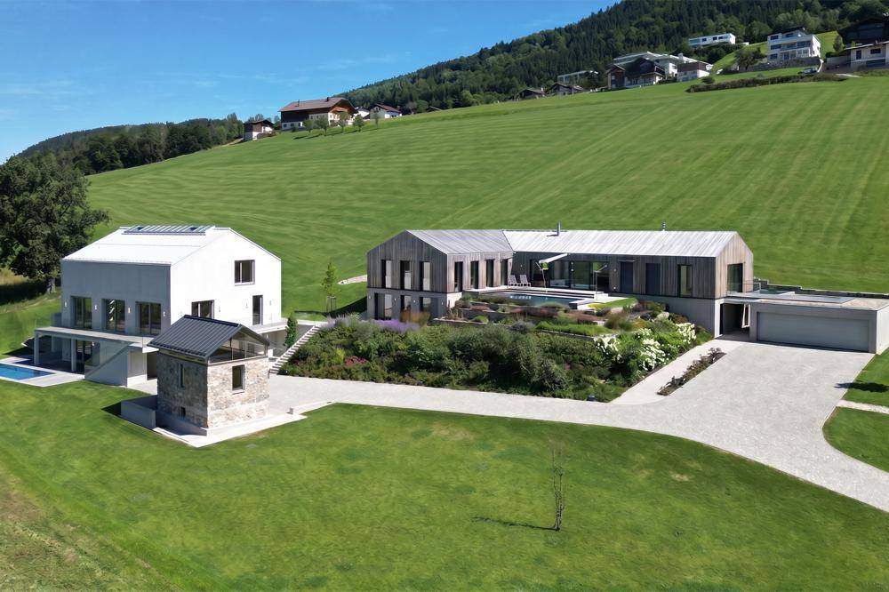Moderne Immobilienanlage mit zwei Hauptgebäuden, einem Poolbereich und gepflegter Gartenlandschaft.