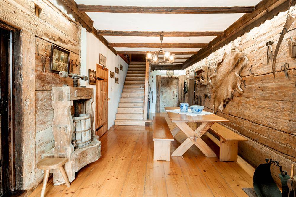 Rustikaler Eingangsbereich mit Holzbalken, Holzwänden und einem traditionellen Esstisch mit Bänken.