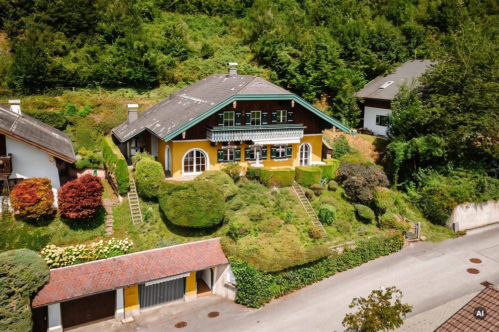 Luftaufnahme eines charmanten Chalets mit gepflegtem Garten und üppiger grüner Umgebung.