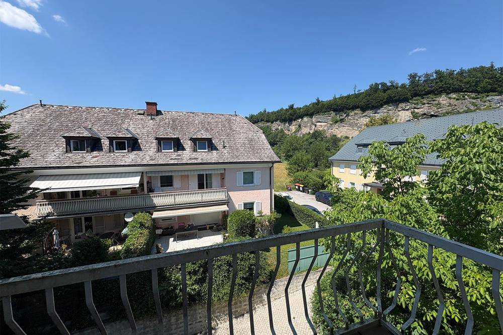 Balkon mit Blick auf die umliegende Wohnbebauung und eine bewaldete Felsformation im Hintergrund.