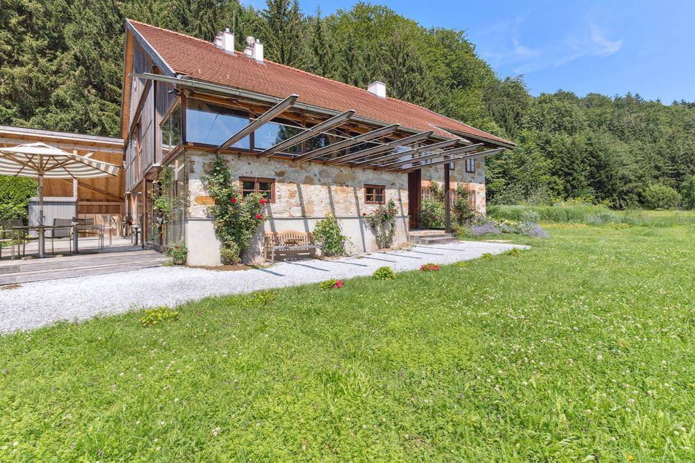 Charmantes Landhaus mit Steinfassade, großer Rasenfläche und einer Terrasse im Grünen.