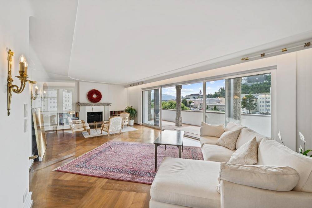 Helles Wohnzimmer mit Kamin, Parkettboden und Zugang zu einer Terrasse mit Stadtblick.